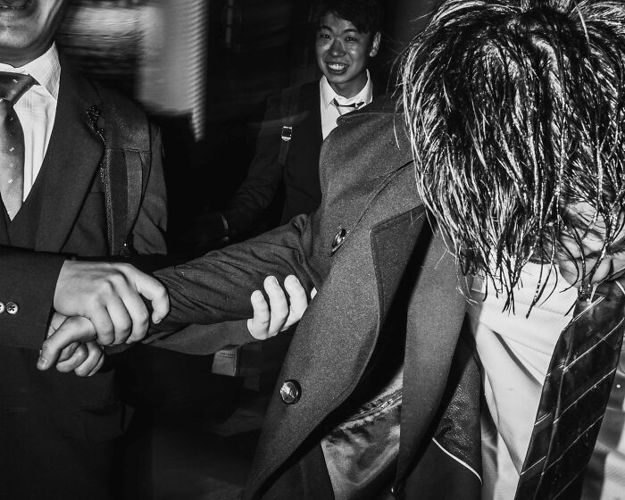 Businessmen in Tokyo capture the city's fast-paced life, showing exhaustion and camaraderie in a busy street scene.