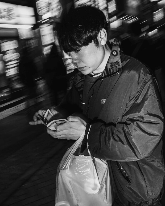 Person in a crowded Tokyo street holding a plastic bag, highlighting fast-paced life.