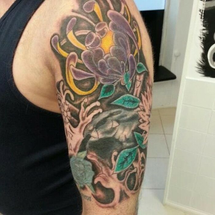 Colorful abstract tattoo with floral elements on a person's upper arm, illustrating a humorous worst tattoo fail.