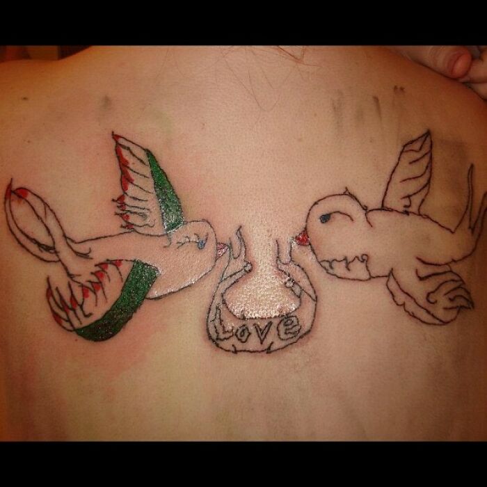 Poorly drawn bird tattoos with the word "love" on skin, showcasing a funny tattoo fail.