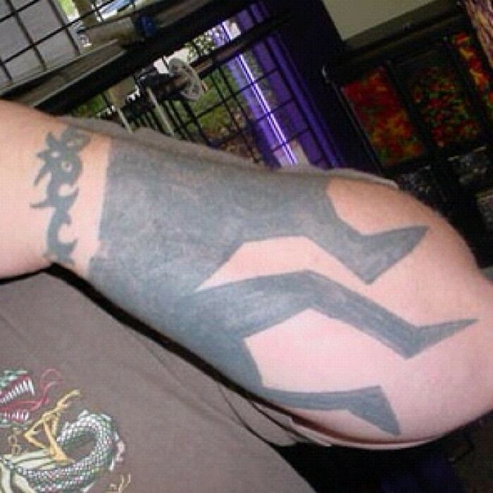 A poorly executed, oversized tattoo covering an arm, resembling abstract shapes; an example of funny worst tattoo fails.