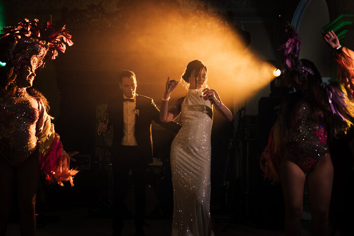 Bride and groom dancing under warm light with performers, capturing a top wedding photo moment of 2024.