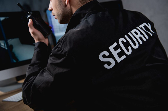 Security expert holding a radio, seated in front of a computer, emphasizing security insights. Security expert holding a radio, seated in front of a computer, emphasizing security insights.