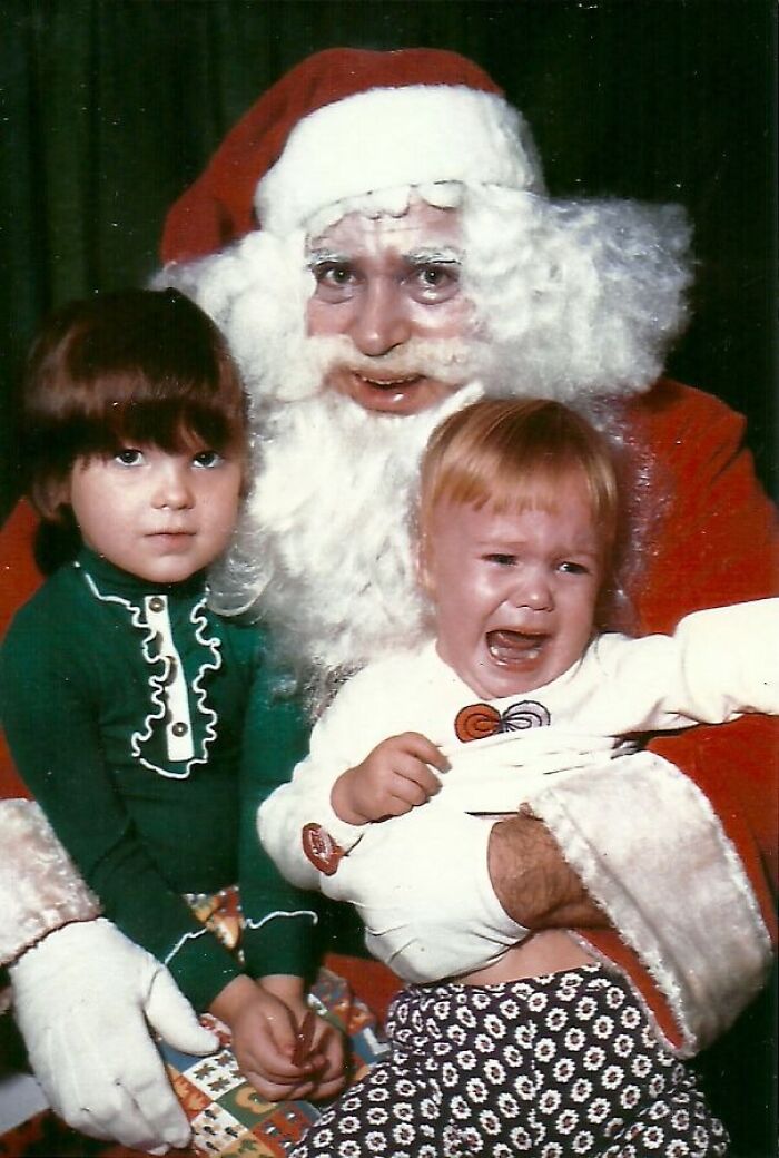 Creepy Santa with a smiling child and a crying toddler on his lap, capturing an unsettling holiday moment.