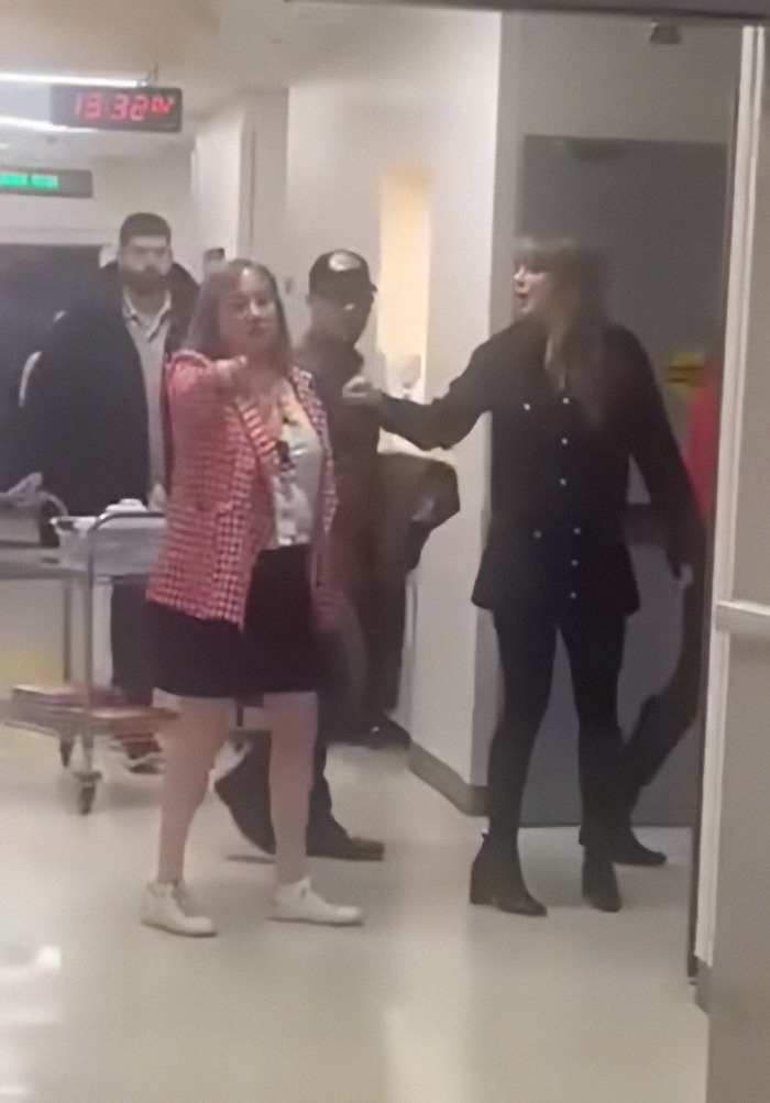 Taylor Swift in a hospital hallway, engaged in discussion, highlighting her visit to a children's hospital.