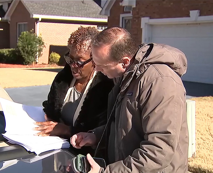 Loletha Hale reviewing documents outside her home with another person, related to squatter issue. Loletha Hale reviewing documents outside her home with another person, related to squatter issue.