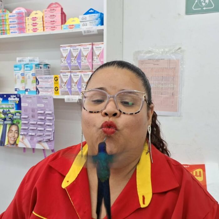 Woman in store wearing glasses and red uniform, interacting with a hummingbird, capturing a magical moment in Brazil. Woman in store wearing glasses and red uniform, interacting with a hummingbird, capturing a magical moment in Brazil.