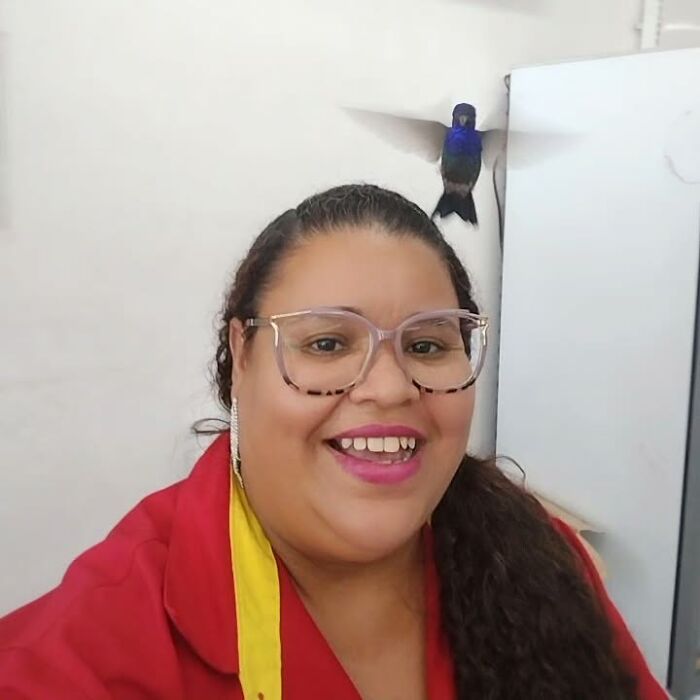 A woman smiling with a hummingbird perched nearby, showcasing a magical friendship. A woman smiling with a hummingbird perched nearby, showcasing a magical friendship.