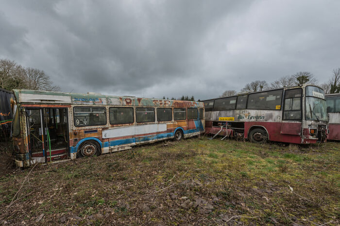 Abandoned Irish ghost buses in a graveyard under a gloomy sky.