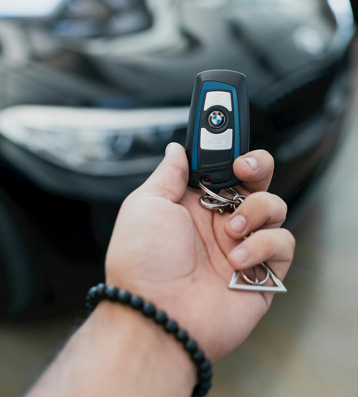 Luxury car key held by a person, highlighting rich kids' lifestyle.