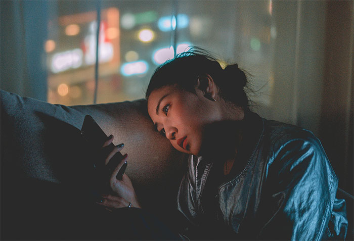 Woman looking at her phone, contemplating family events with her ex during Thanksgiving and Christmas.