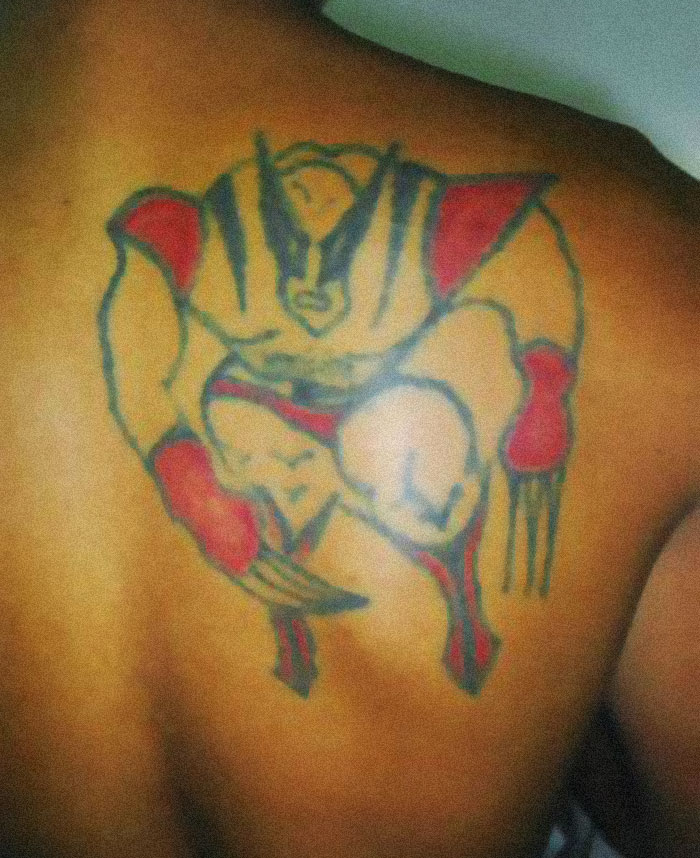 A tattoo fail depicting a superhero with distorted features and uneven lines on a person's back.