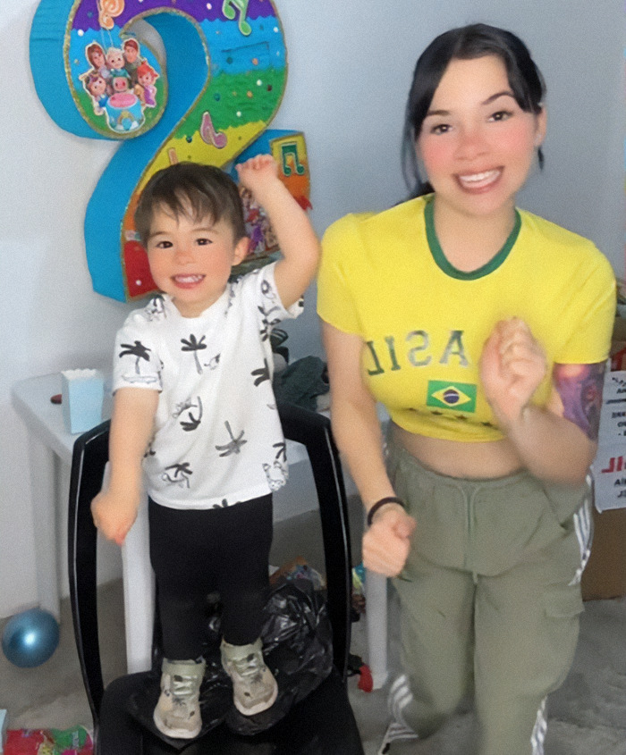Nebrazkha and her child smiling in front of colorful birthday decorations, celebrating with joy.