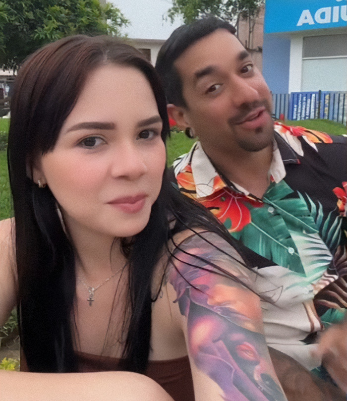 Nebrazkha and her husband smiles outdoors, with a focus on their colorful clothing and tattoo.