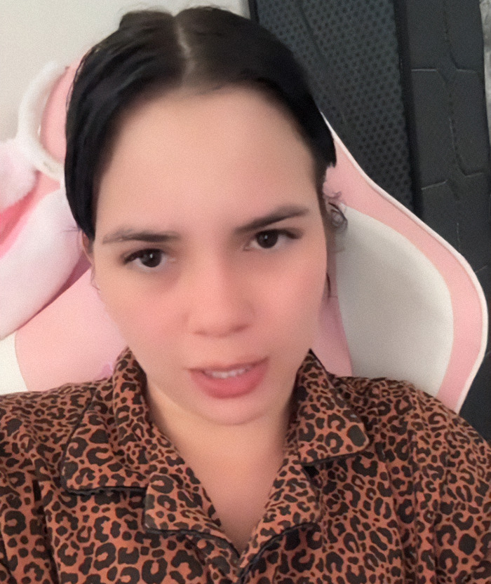 Nebrazkha in leopard print shirt with concerned expression, seated in a pink chair.