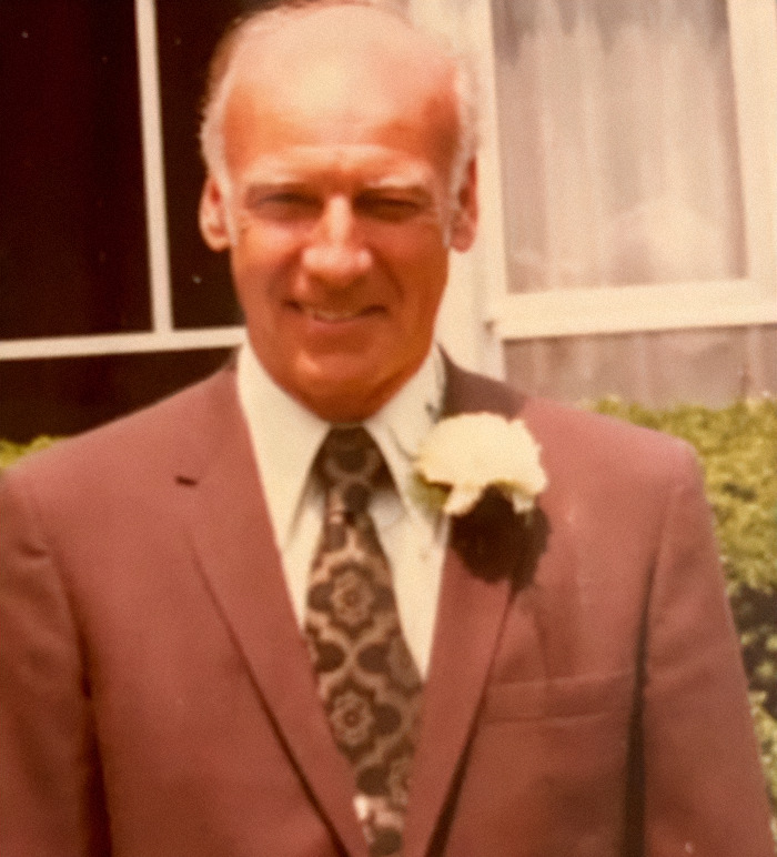 Elderly man in a suit smiling, representing reuniting with family after 75 years.