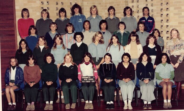 Group of '70s high school students posing for a class photo, wearing diverse attire typical of the era.