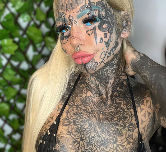 Australia's most tattooed woman posing, showcasing extensive ink designs on her face and body.