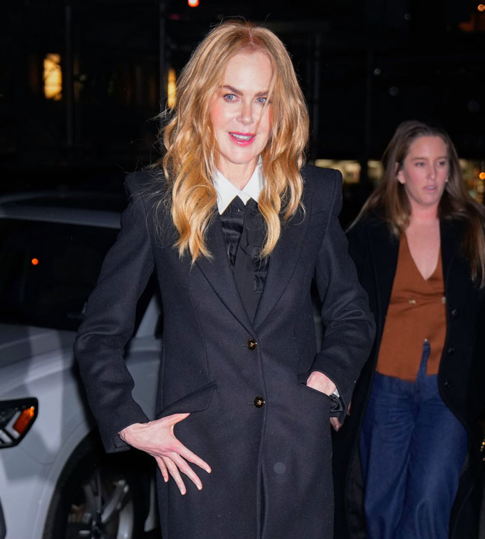 Woman in a black coat with long blonde hair, outdoor evening setting, related to Aquaman 2 cast.