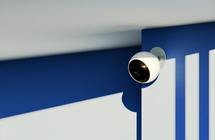 Surveillance camera on a blue and white wall, symbolizing security concerns.