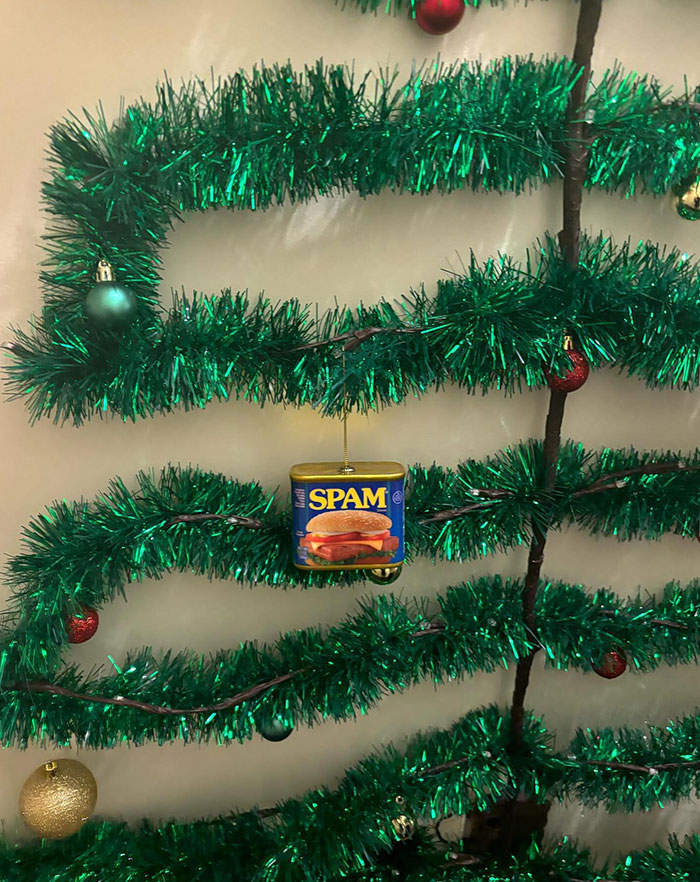 Green tinsel with ornaments and a can of Spam hanging, resembling a unique take on a holiday decoration.