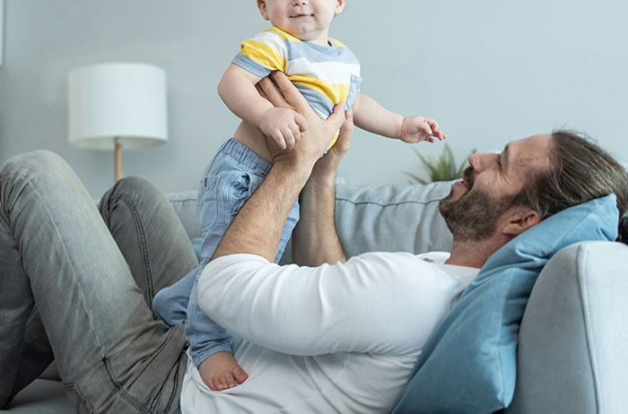 Father and child enjoying playful time on a couch, illustrating tender moments and life choices.