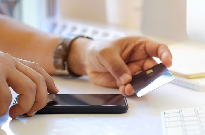 Person holding a credit card and smartphone, illustrating impactful financial decision-making.