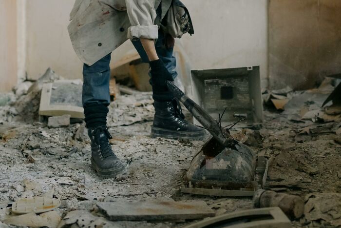 Person breaking old electronics in abandoned building, illustrating bad habit.