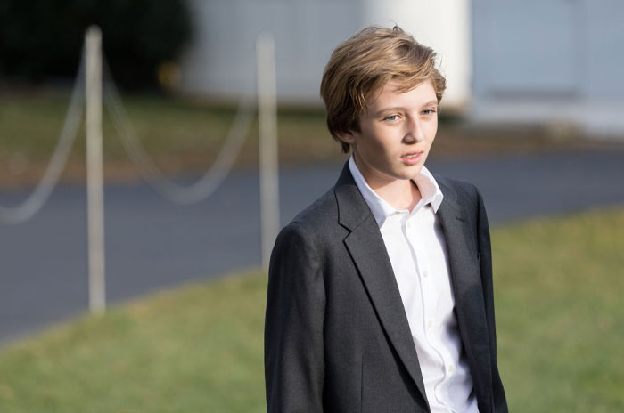Young Trump outdoors in a gray blazer and white shirt, with a pensive expression.