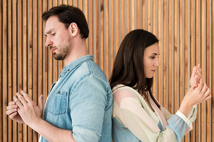 Two people stand back to back, looking down, reflecting on biggest regrets from their 20s.