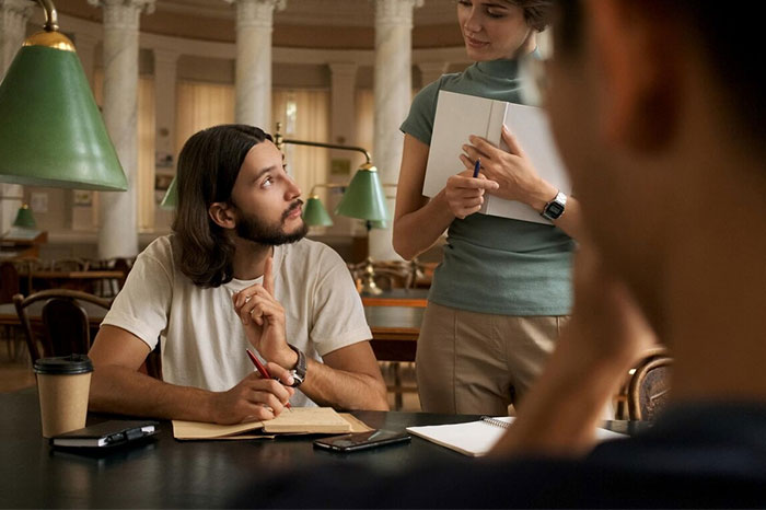 Young adults discussing plans in a library, highlighting common regrets from their 20s.