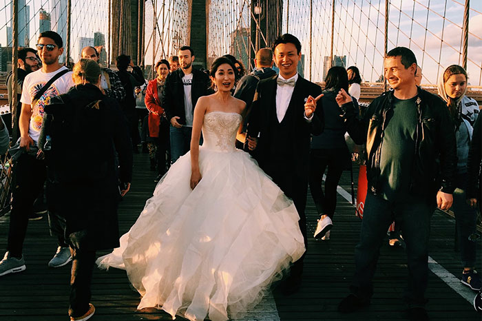 A couple in wedding attire on a crowded bridge, capturing moments of joy amidst people's biggest regrets from their 20s.