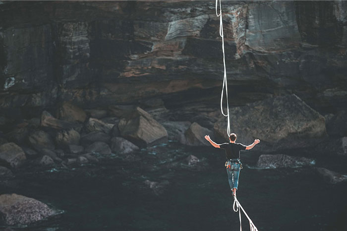 Person tightrope walking in a canyon, symbolizing biggest regrets and risks faced in their 20s.