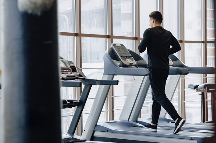 Man exercising on treadmill in gym, possibly reflecting on biggest regrets from people's 20s.