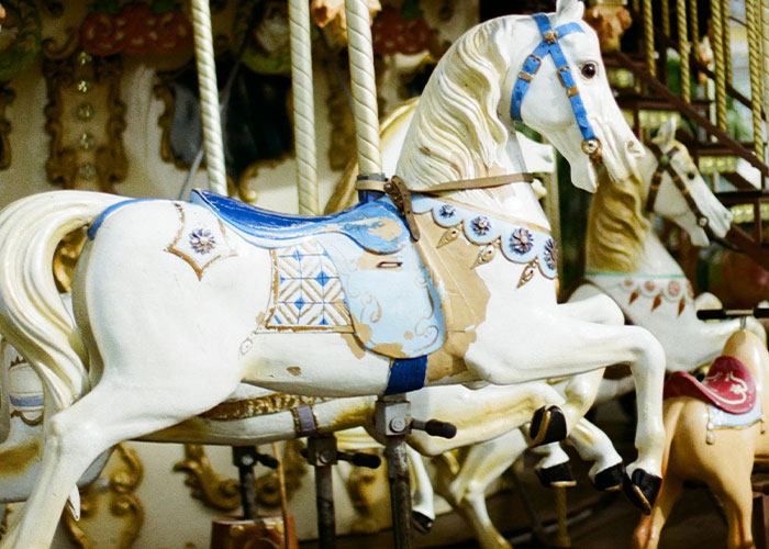 Vintage carousel horse displayed inside a home, featuring ornate decorations and a blue saddle.