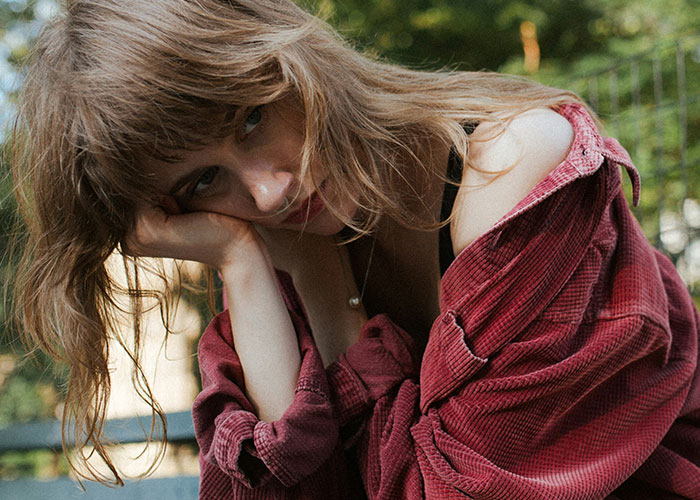 Woman in a red shirt looking contemplative after receiving a disappointing gift from her partner.