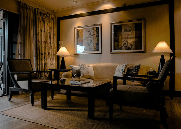 Cozy apartment living room with art on the wall, warm lighting, and cushioned seating. Cozy apartment living room with art on the wall, warm lighting, and cushioned seating.