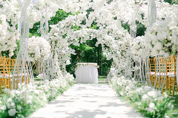 Wedding ceremony setup with floral archways and white flower decorations.
