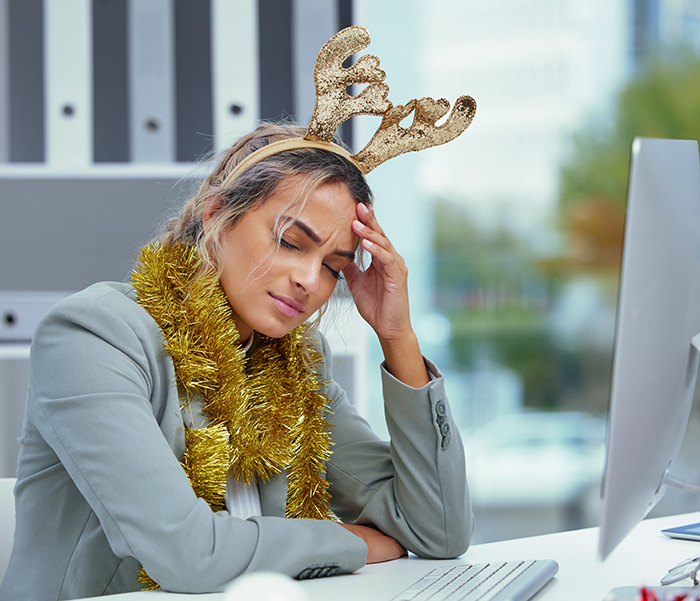 A stressed woman in Christmas attire, highlighting workplace discrimination around holiday coverage.