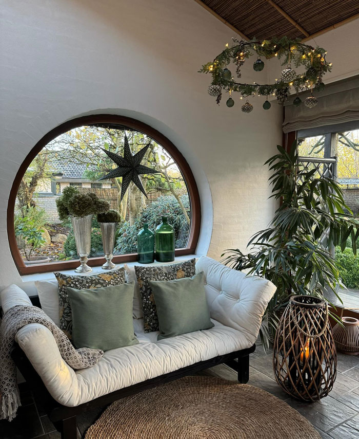 Cozy living room with holiday greenery and star decor by a circular window, showcasing Christmas decorating ideas.
