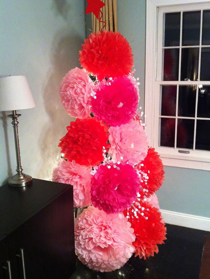 Colorful pom-pom styled Christmas tree idea with red and pink decorations in a cozy room corner.