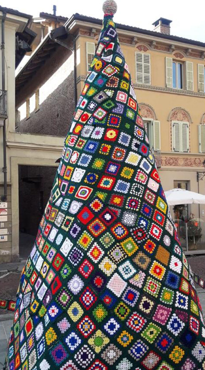 Colorful crochet Christmas tree outside a building.