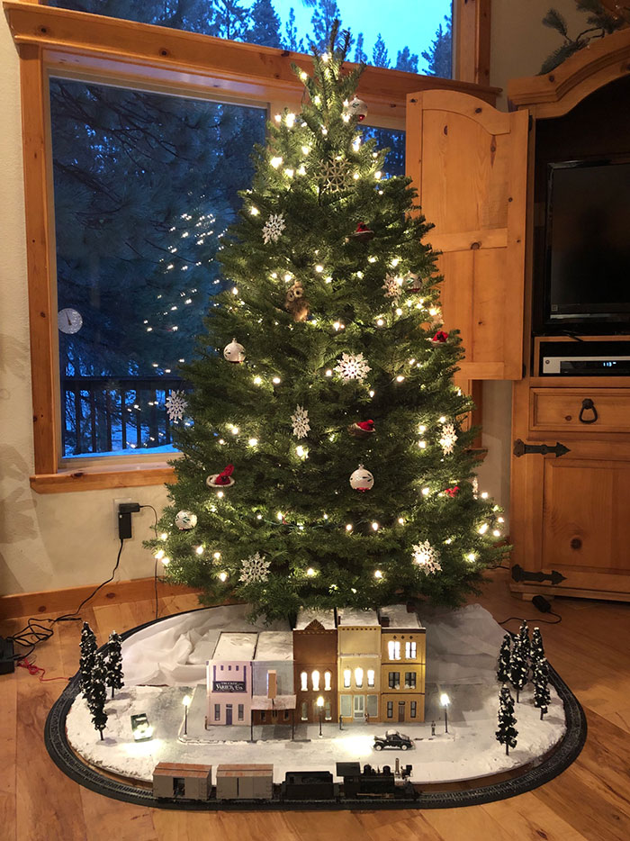 Decorated Christmas tree with lights, ornaments, and a miniature village scene beneath it, perfect for Christmas tree ideas.