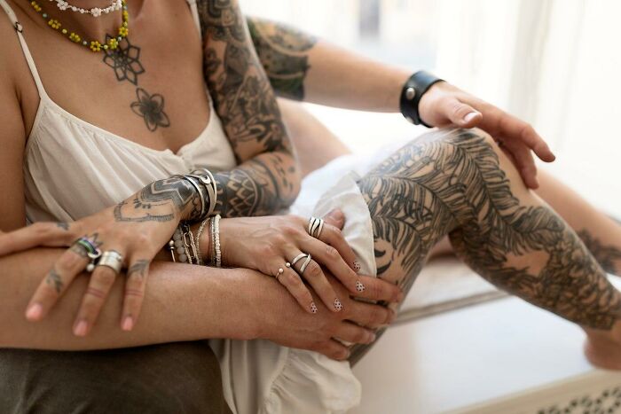 Tattooed arms and legs intertwined, showcasing unique personal expression and style.