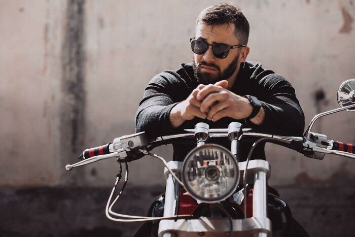 Man in sunglasses sitting on a motorcycle, representing the romanticized but actually awful aspects of biker culture.