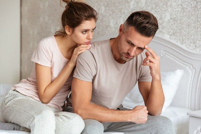 Concerned couple sitting on a bed, reflecting on a terrible Christmas experience.