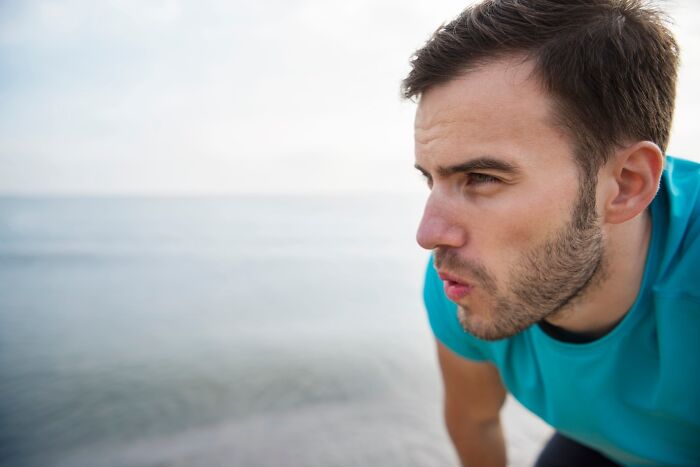 A person in a blue shirt standing by the water's edge, showcasing a reflective moment.