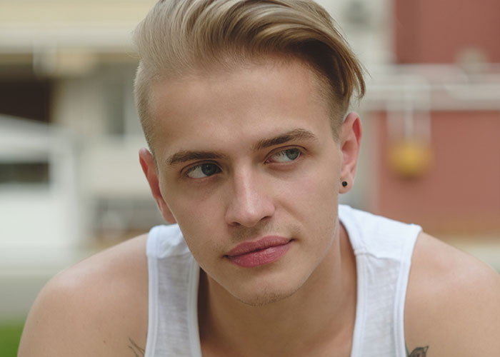 Person with trendy hairstyle in a white tank top, outdoors, representing a shift in partner perception.
