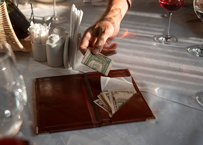 A hand holding dollar bills over a table setting, suggesting a change in perception of a partner.