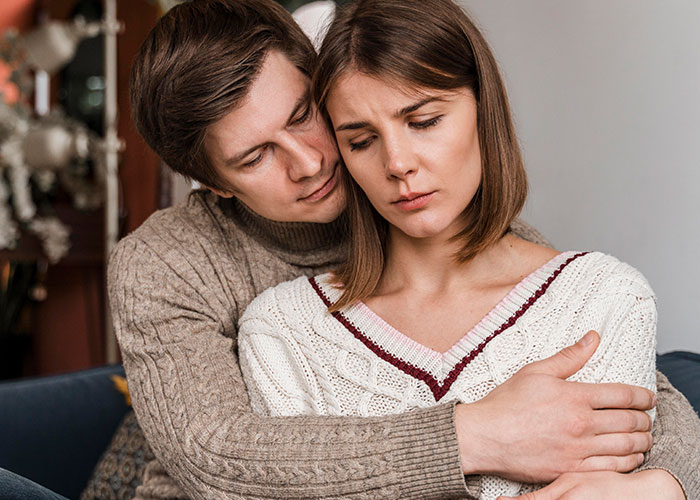 A couple sitting together; the man comforts the woman, reflecting on surprising partner comments.